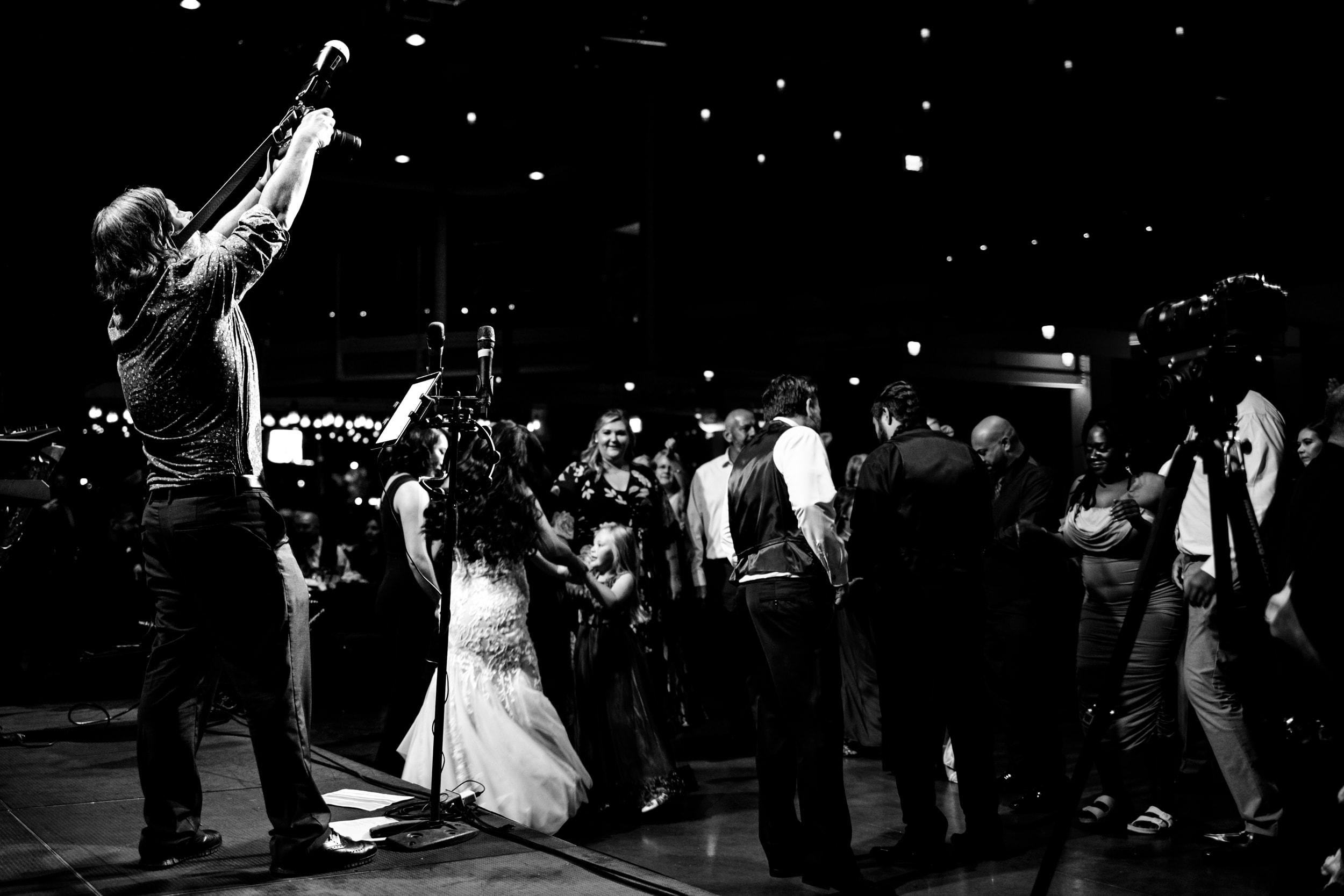 Black-and-white photograph of Steve performing for a dancing wedding crowd.