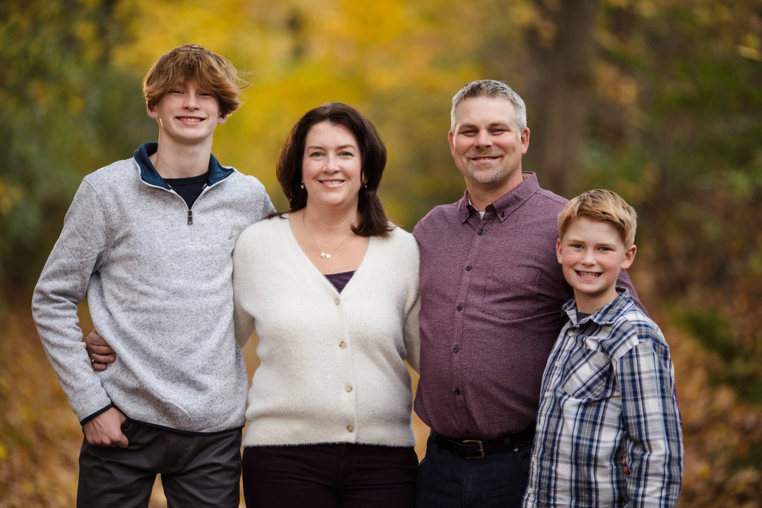 Family portrait in autumn outdoor setting with smiling parents and children.