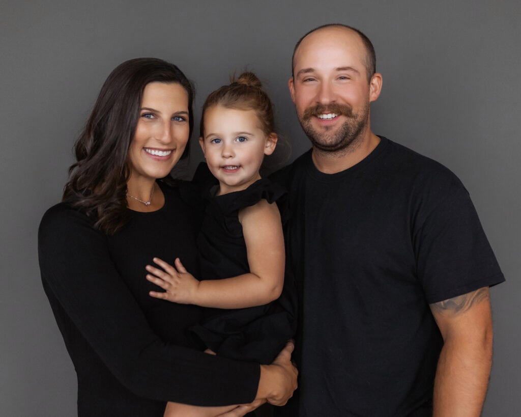 Happy family portrait featuring mother, father, and daughter smiling warmly together.
