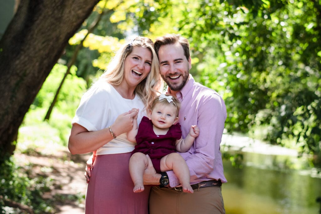 Family enjoying a sunny day outdoors with a young child by a river.