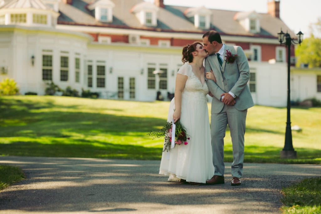 Bride and groom kissing outside historic Cameron Estates mansion during fall Lancaster County wedding.