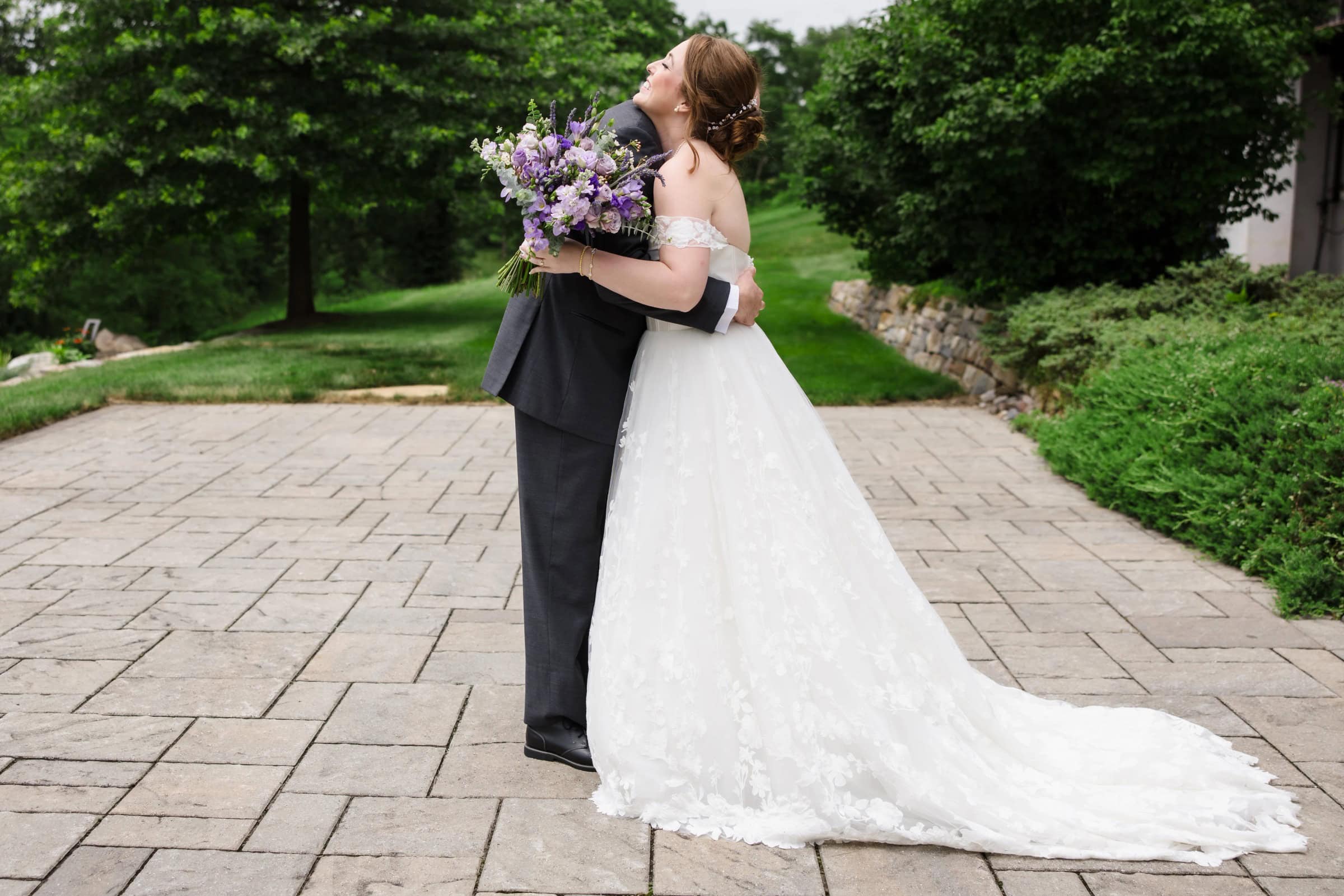 Bride and groom embracing on a stone pathway, bride holding purple bouquet, groom in dark suit. — Wedding at Glasbern Inn, Fogelsville, PA
