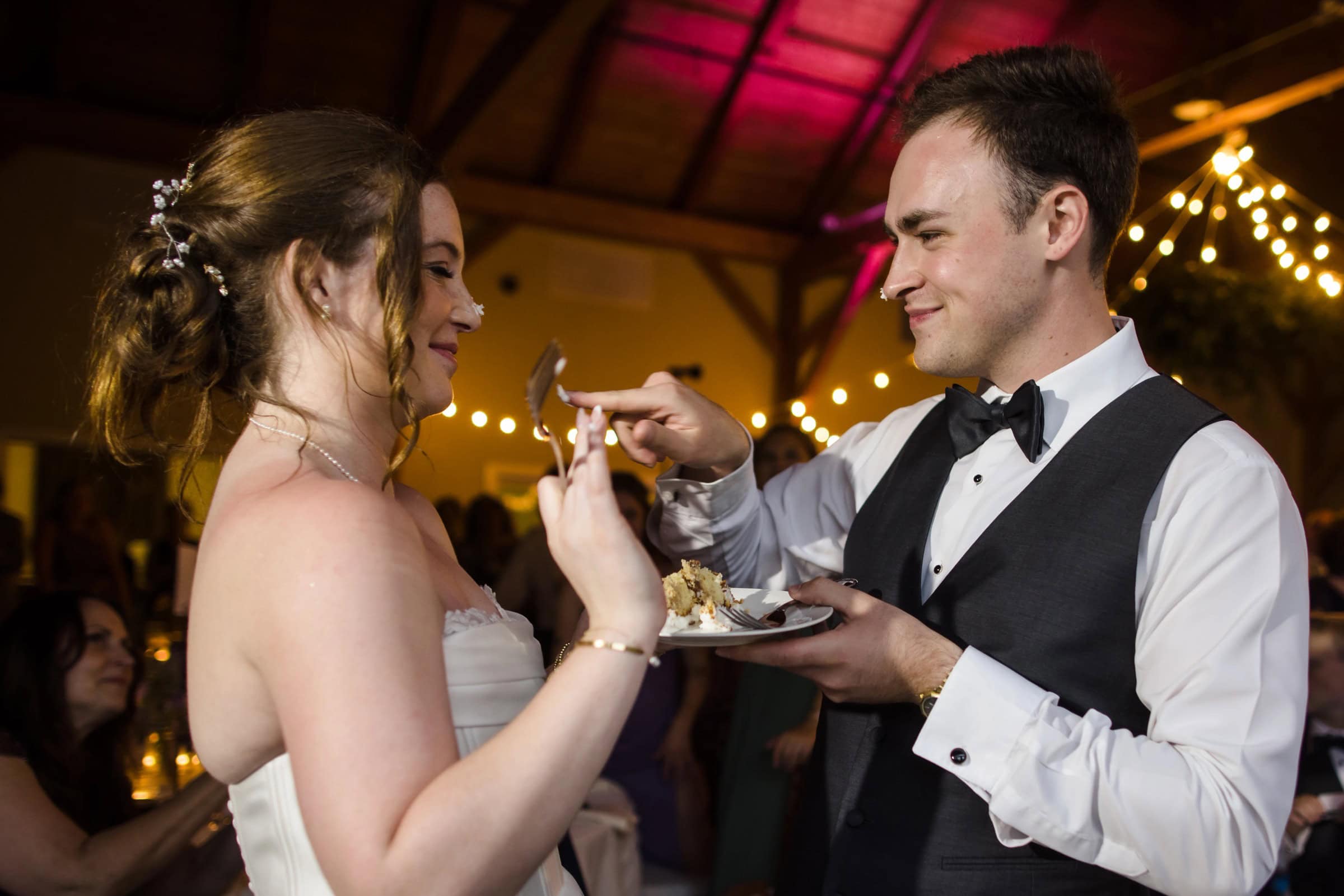 Bride and groom feed each other cake at their reception, smiling and making eye contact. — Wedding at Glasbern Inn, Fogelsville, PA