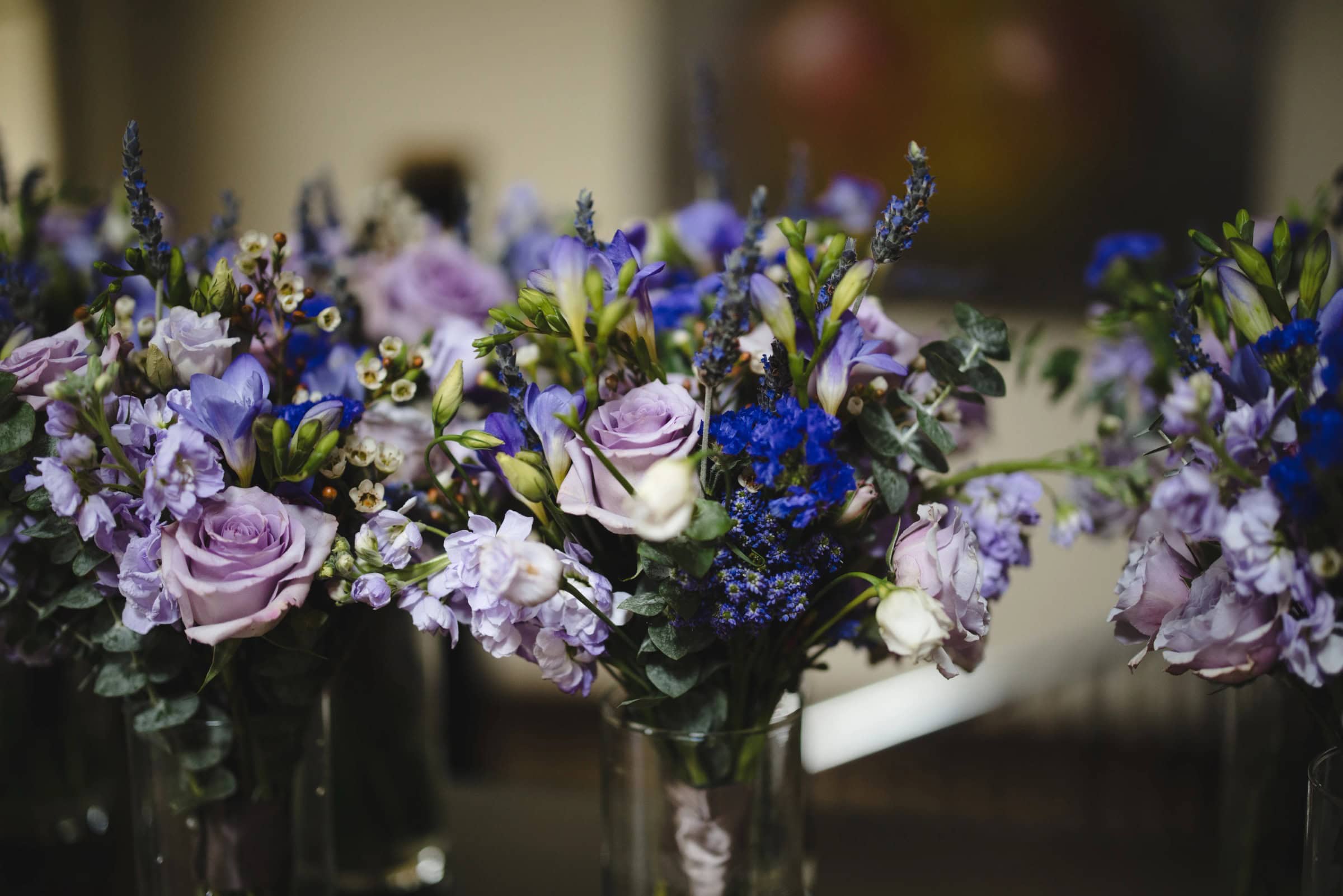 Floral arrangement displayed in clear glass vases, showcasing layered blooms in purple, lavender, and blue tones. — Wedding at Glasbern Inn, Fogelsville, PA