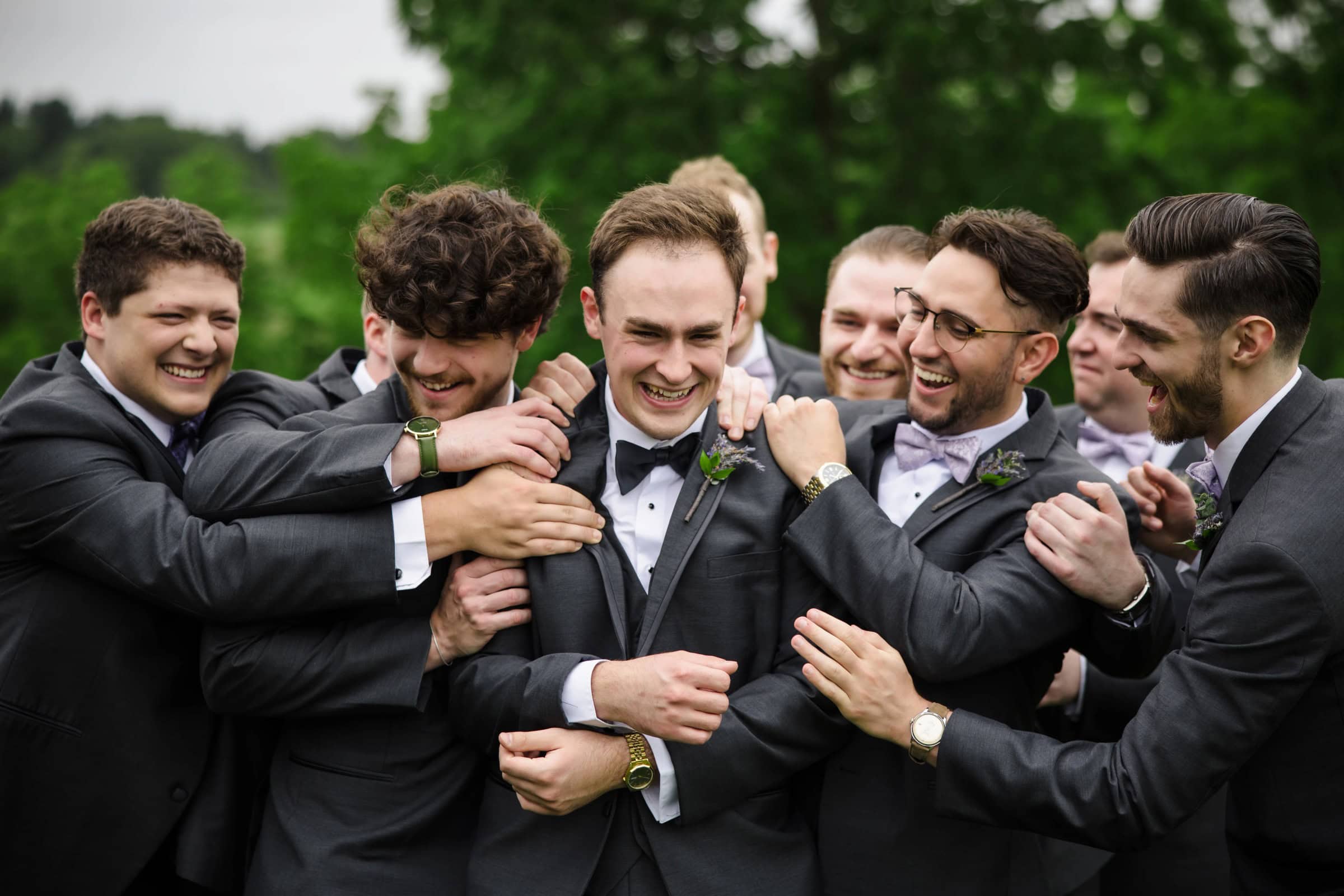 Groom and groomsmen embrace and laugh together outdoors, arms linked around shoulders in celebration. — Wedding at Glasbern Inn, Fogelsville, PA