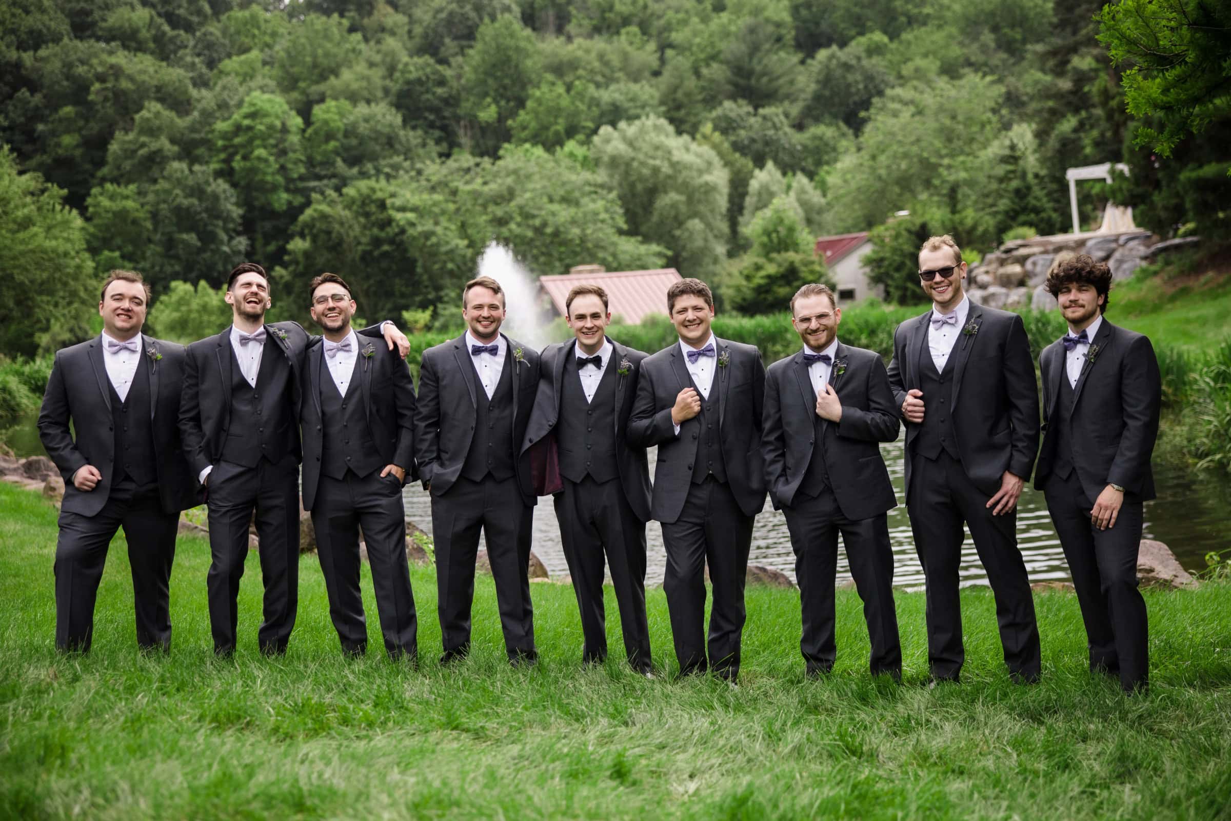 Ten groomsmen stand in a line across a grassy hillside, posing formally for a group portrait. — Wedding at Glasbern Inn, Fogelsville, PA