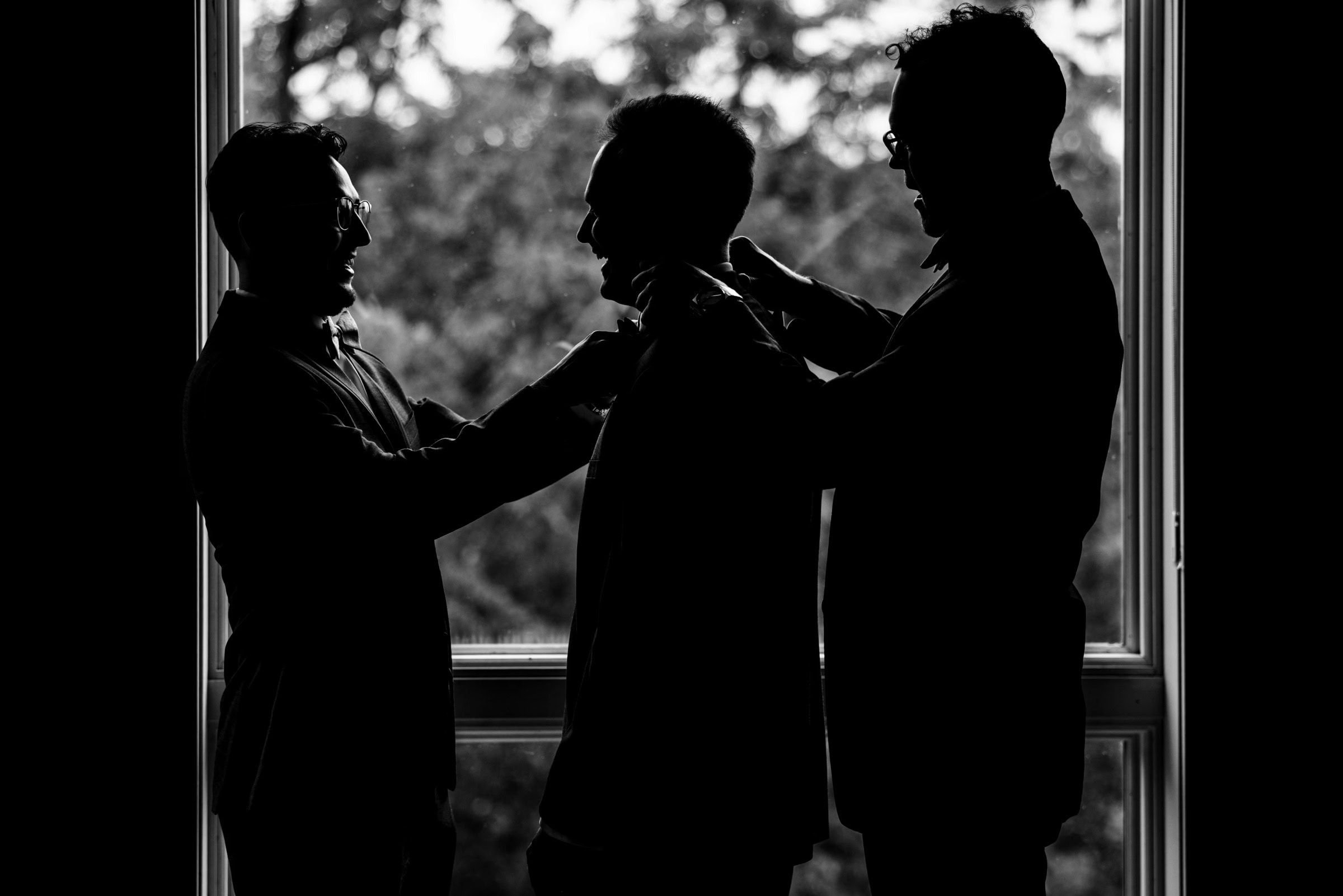 Three people in silhouette standing at a large window, engaged in conversation or interaction. — Wedding at Glasbern Inn, Fogelsville, PA