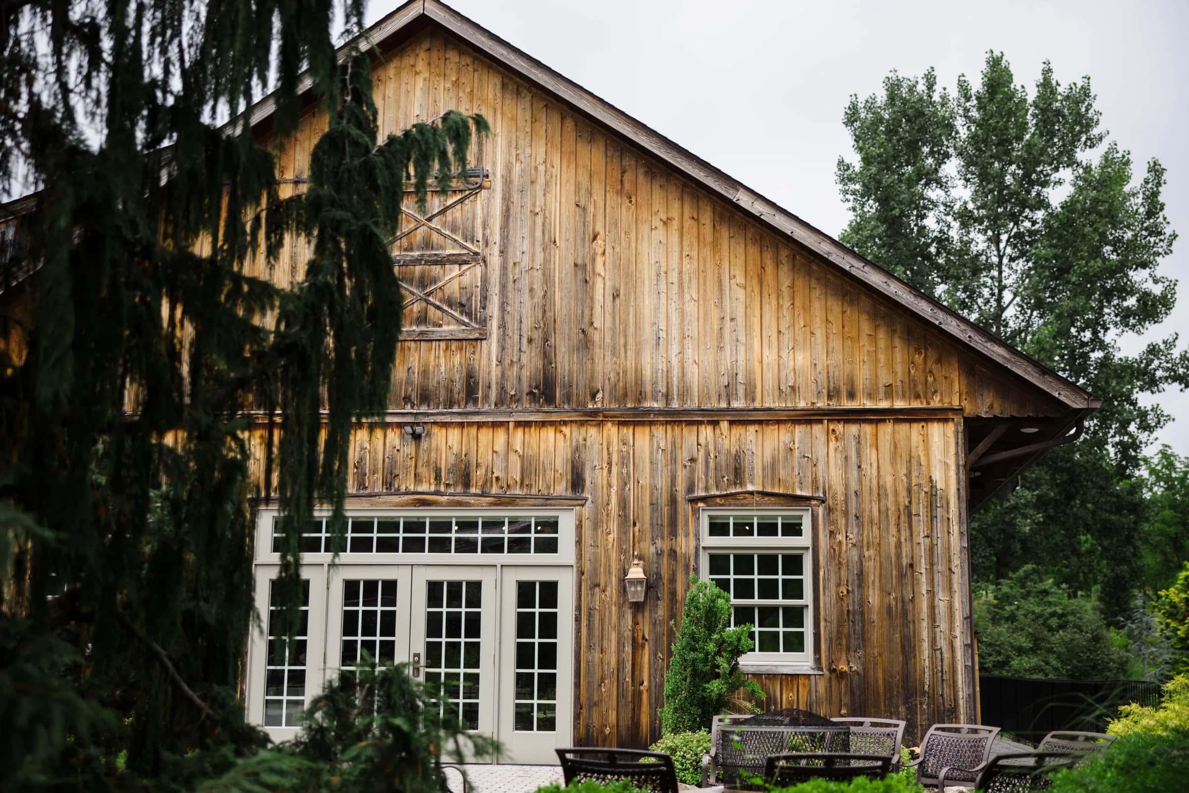 Wooden barn structure stands weathered and ivy-covered in a lush garden setting. — Wedding at Glasbern Inn, Fogelsville, PA
