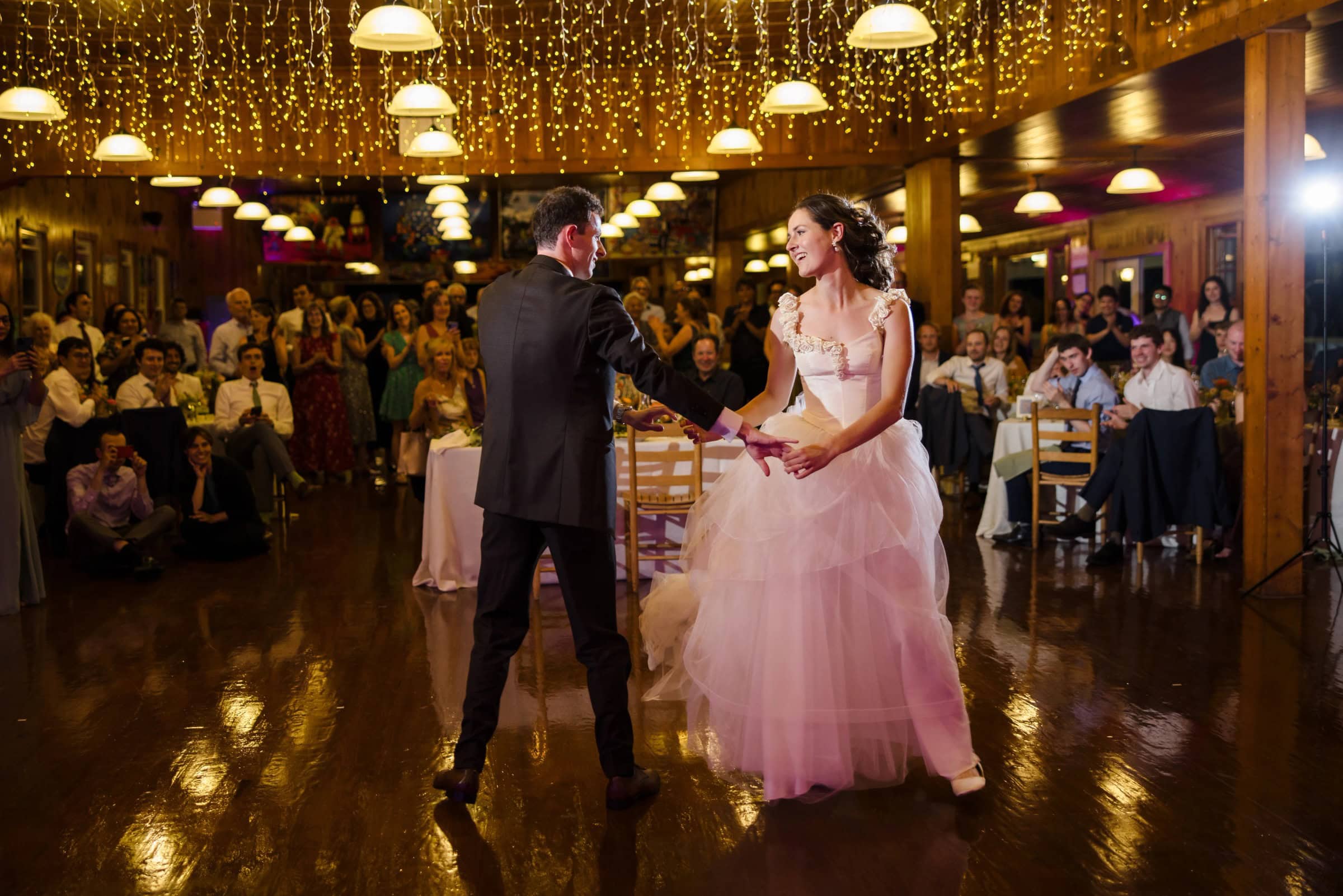 Bride and groom share their first dance on the reception floor, surrounded by watching guests. — Wedding at Tyler Hill Camp, Tyler Hill, PA