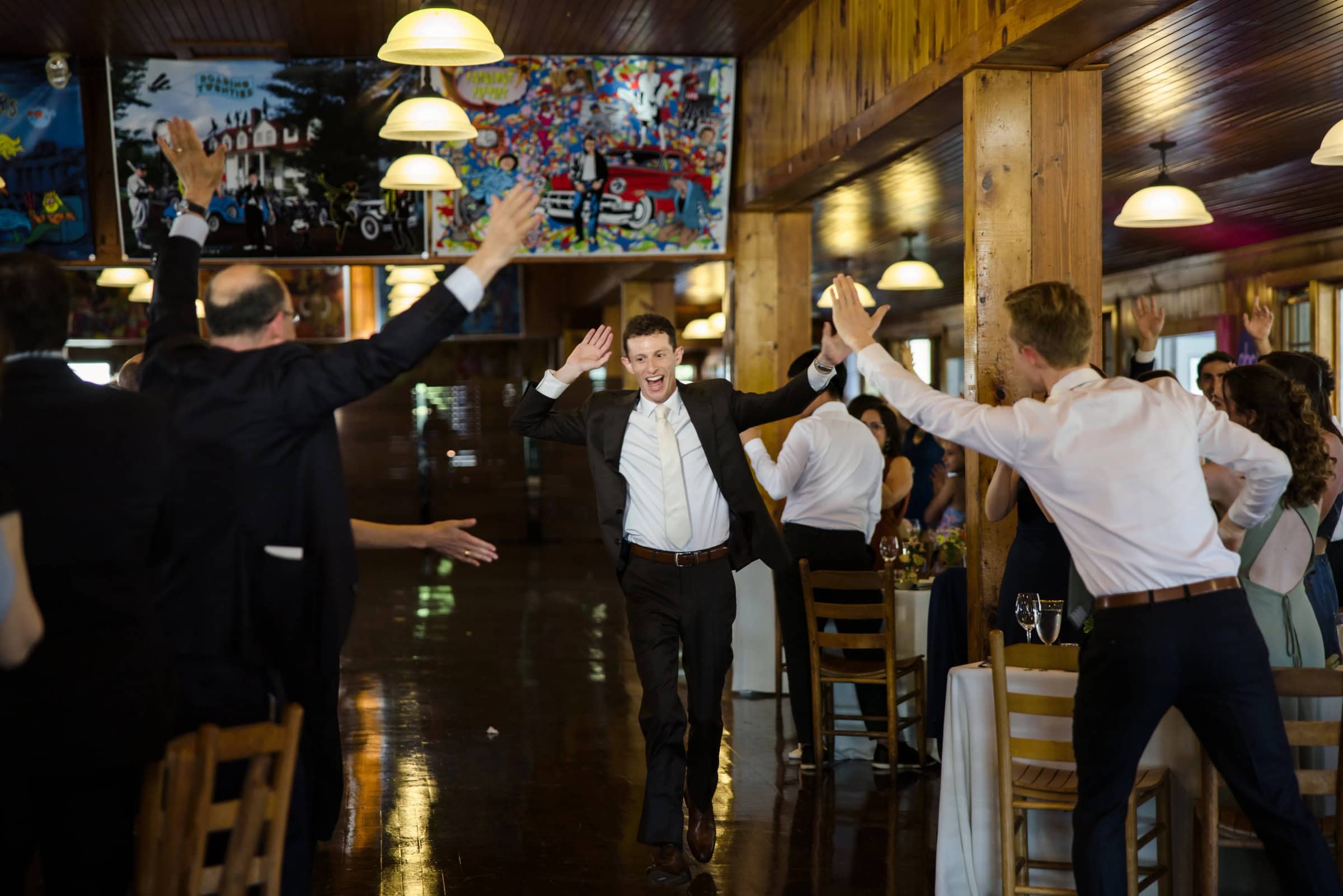 Guests and groomsmen celebrate with raised arms during a reception dance, cheering and clapping. — Wedding at Tyler Hill Camp, Tyler Hill, PA