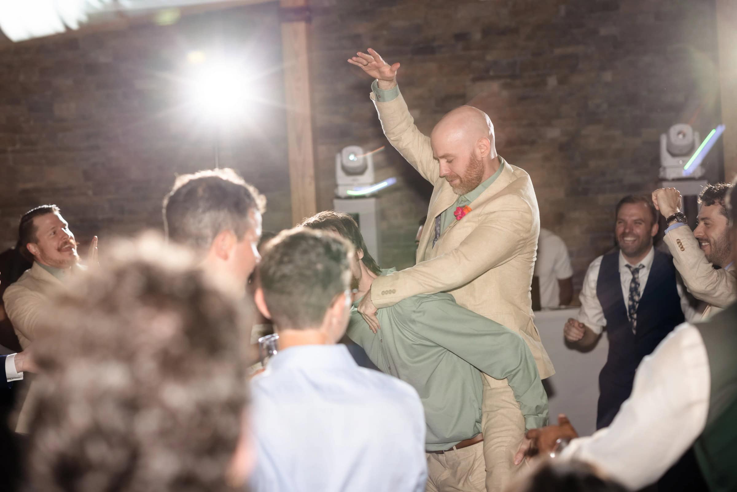 Man dancing energetically with guests surrounding him at an indoor celebration, arm raised mid-movement. &mdash; Wedding at Landmark Tavern at Stonehouse, Warren, NJ