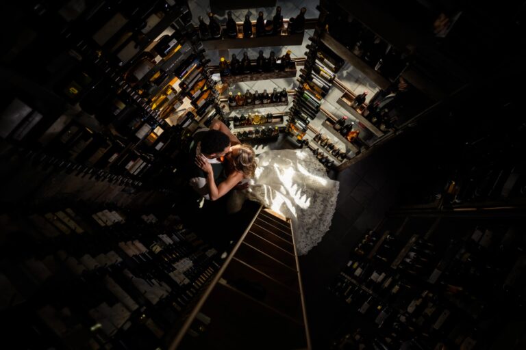 Person standing on a narrow ledge high above a city street at night, looking down at the illuminated urban landscape below. &mdash; Wedding at Landmark Tavern at Stonehouse, Warren, NJ