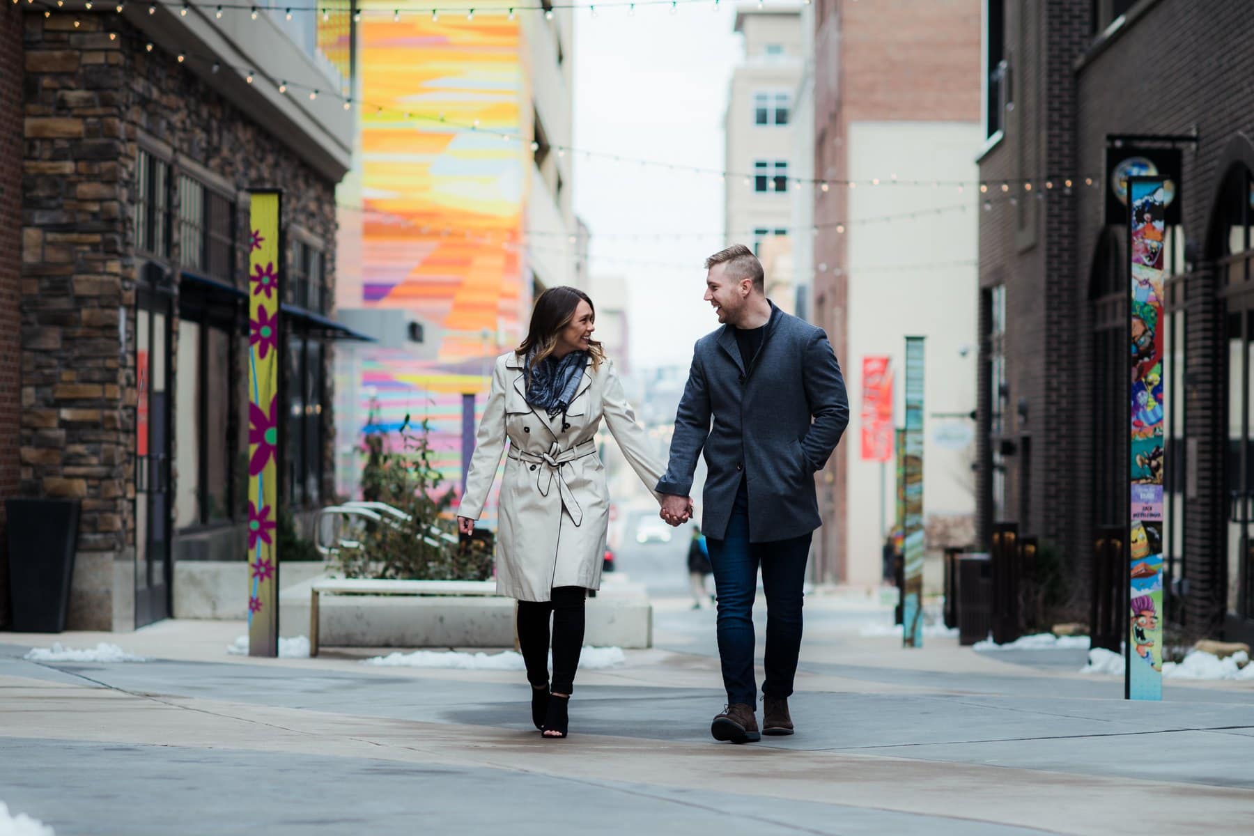 Couple walking hand in hand through Allentown ArtsWalk with colorful murals and string lights.