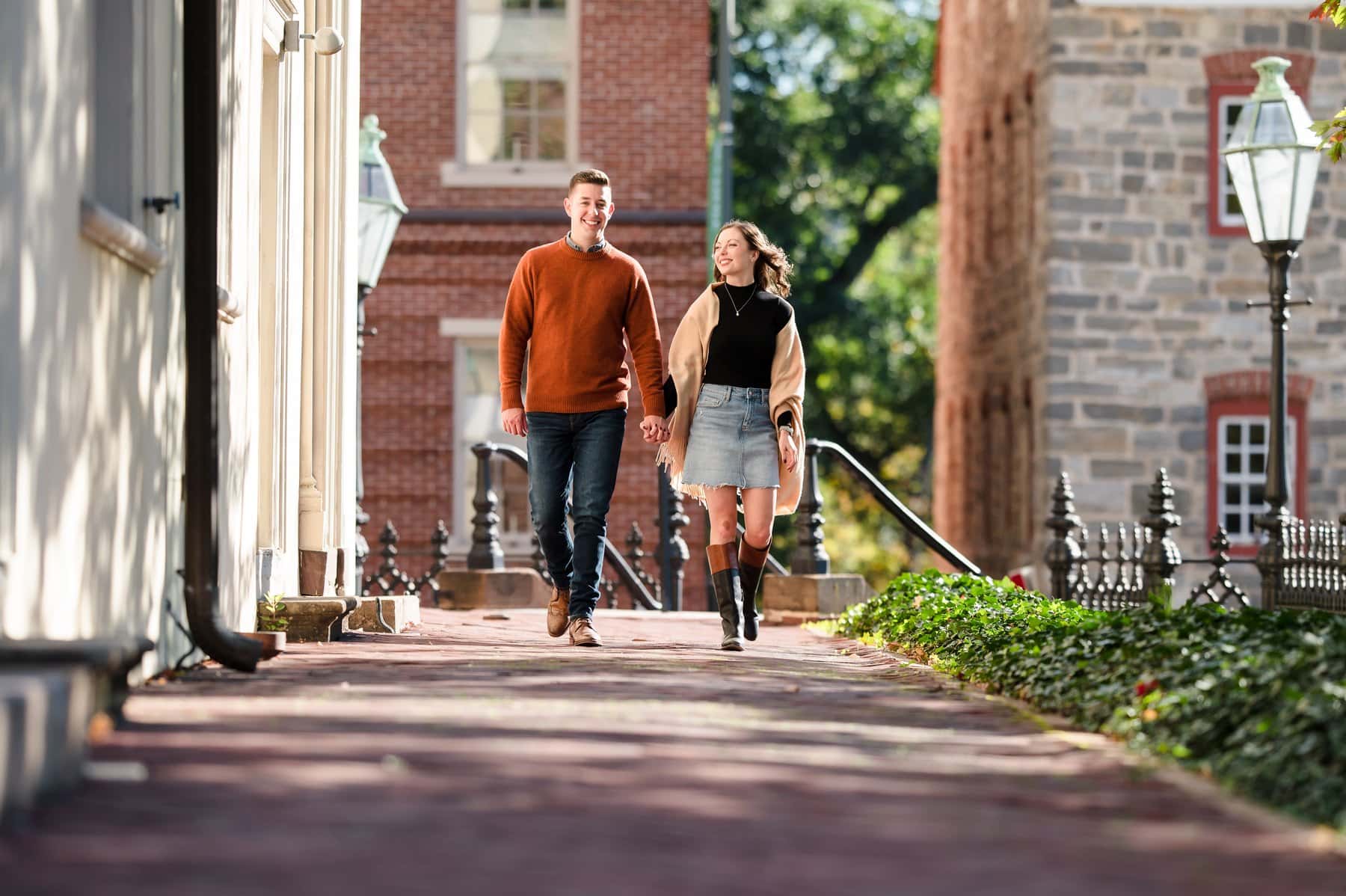 Couple walking hand in hand along a brick walkway between historic buildings in Bethlehem.