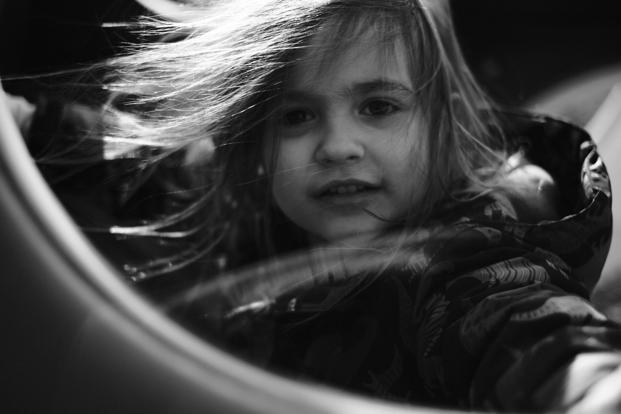 Candid black-and-white portrait of a child with windblown hair.