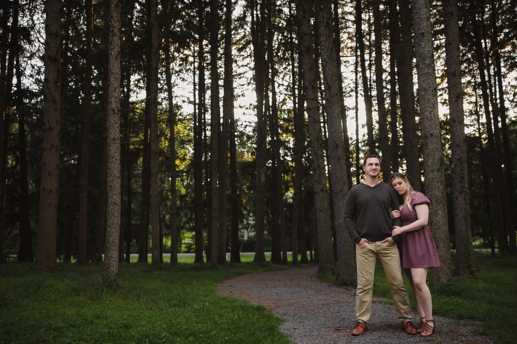 Couple standing on a path among the tall pine trees at Kalmbach Park.