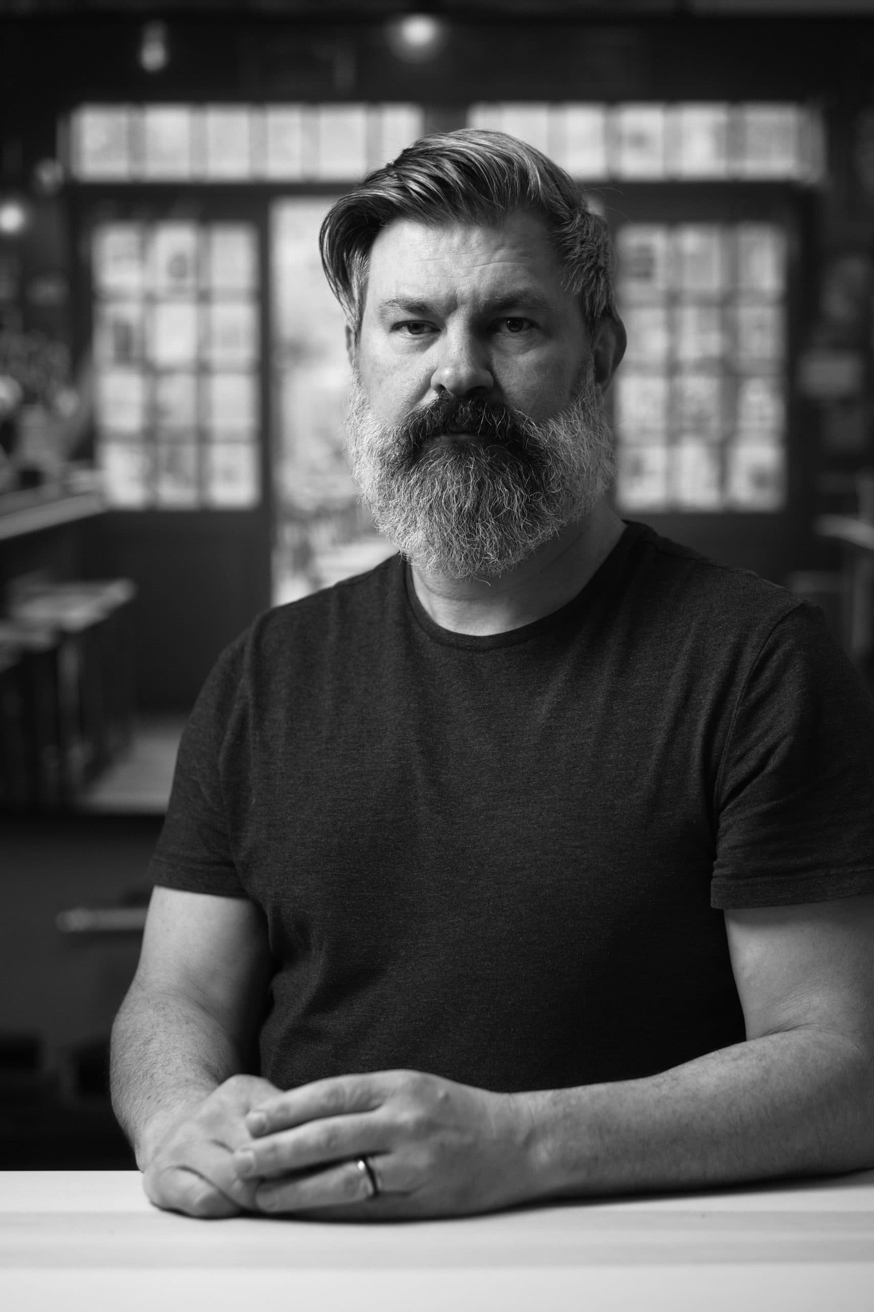 Black-and-white portrait of Steve Braglio seated at a table.